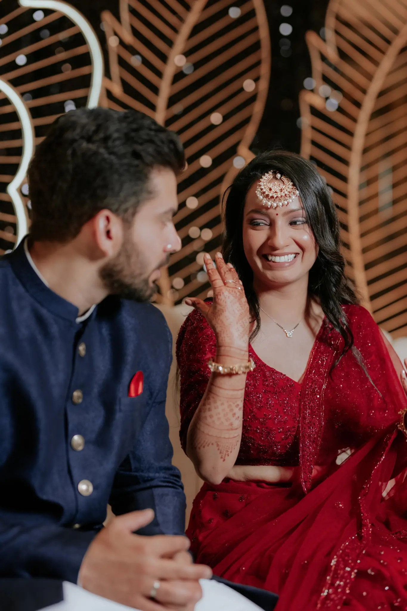 Smiling ring ceremony couple sharing a joyful moment in coordinated red and navy outfits