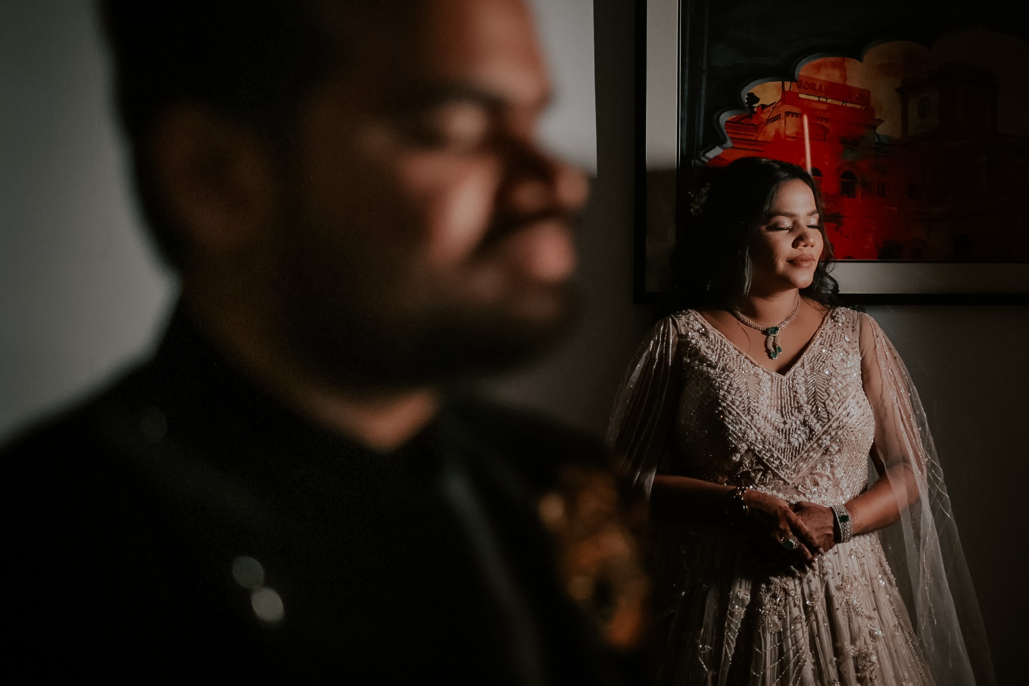 Engaged couple posing by a window in dramatic light